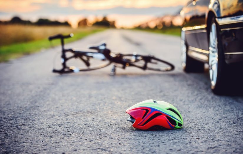 A persons Helmet Laying On The Ground With A Bicycle In The Background