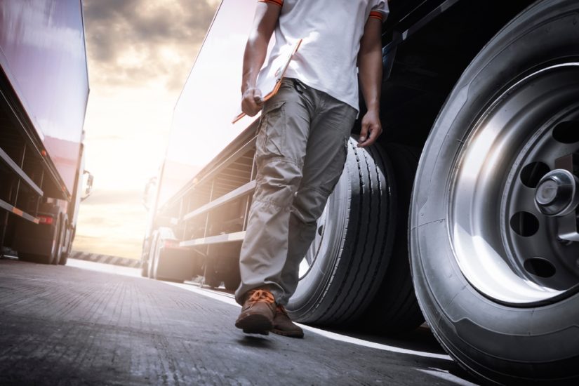 Truck Driver With Tablet Walking Between Trucks