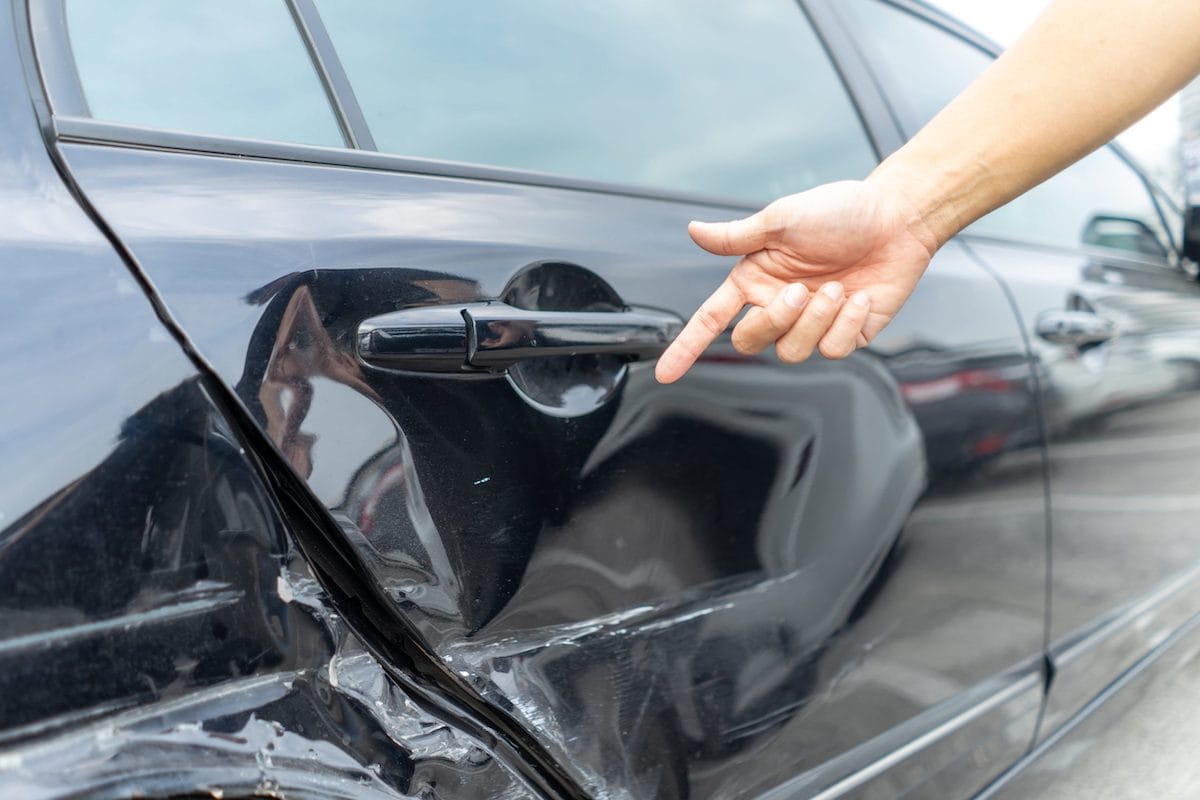 Finger Pointing at Damage Caused to a Car From a Side Collision