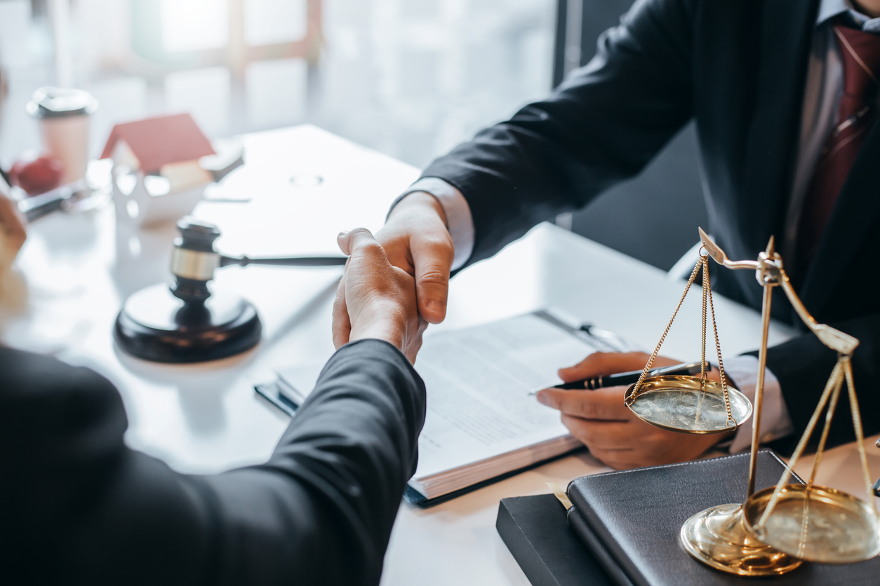 Two people shaking hands over a desk