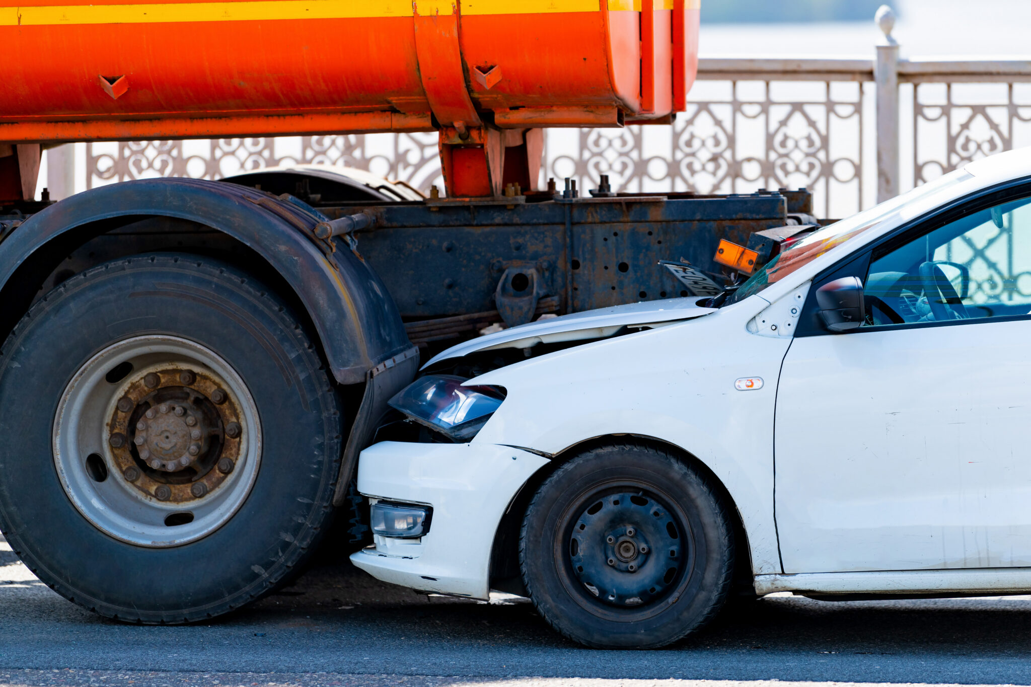 A Car Underneith A Big Truck S Tires And Bumper